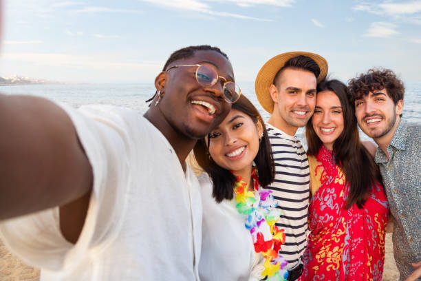 grupa szczęśliwych, wielorasowych przyjaciół patrzących w aparat robi sobie selfie na świeżym powietrzu na plaży. letnia impreza. - party beach indian ethnicity adult zdjęcia i obrazy z banku zdjęć