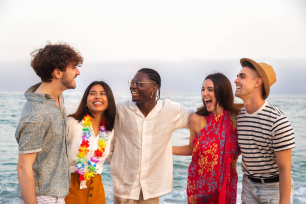 wielorasowi przyjaciele bawiący się na plaży. obejmując się, śmiejąc się w pobliżu oceanu. - party beach indian ethnicity adult zdjęcia i obrazy z banku zdjęć