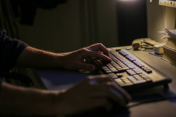 Business man working late at office at computer typing on keyboard. Male using computer for financial reports, working late overtime