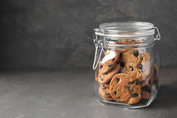 istock Delicious chocolate chip cookies in glass jar on grey table, space for text 1453135911