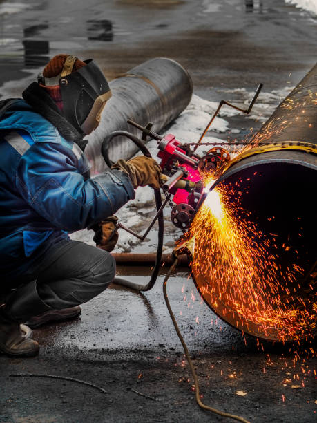 o soldador de trabalho corta metal e faíscas voam. corte a gás de tubos de grande diâmetro com acetileno e oxigênio. corte industrial de metais na indústria de petróleo e gás - acetylene - fotografias e filmes do acervo