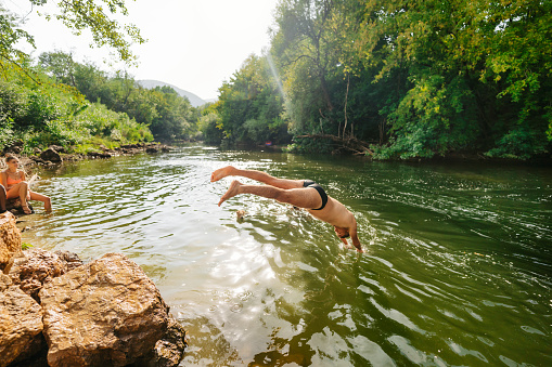 Photo of friends spending a day on the river, jumping from the cliff