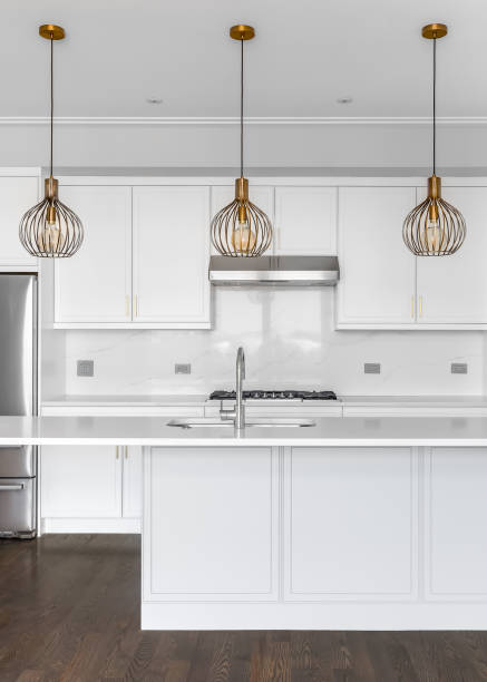 istock A white kitchen with gold lights hanging above the island. 1453138295