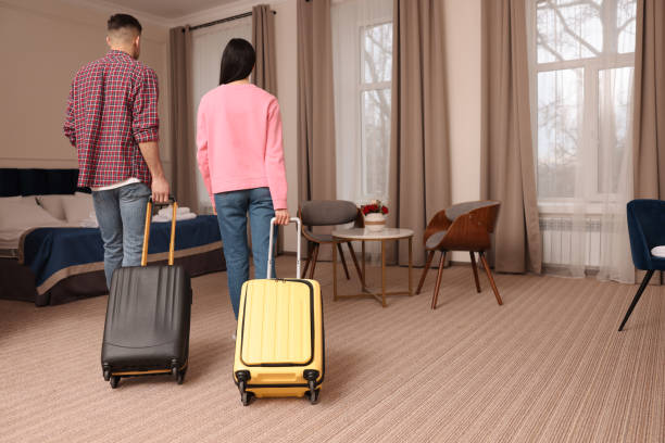 istock Couple with suitcases walking into hotel room, back view 1453138923
