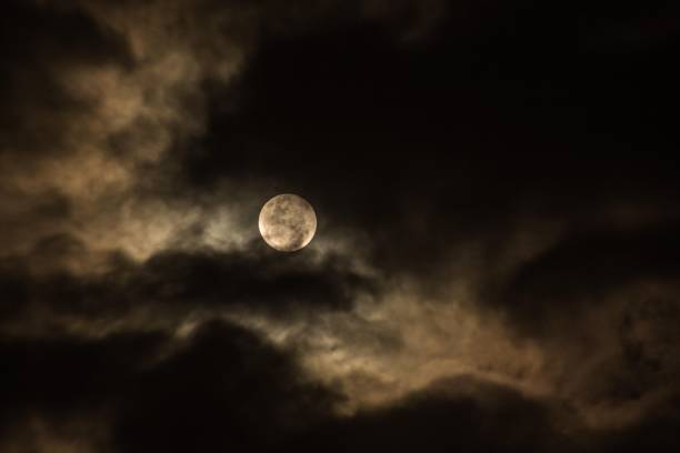 istock Beautiful view of a full moon lighting between the dark night clouds 1453140339