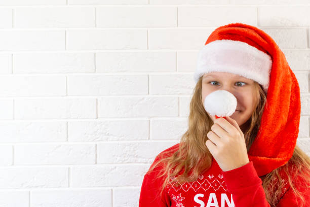 Christmas teenage girl in santa hat makes a funny face. Winter holidays. Merry Christmas and New Year. Christmas teenage girl in santa hat makes a funny face. Winter holidays. Merry Christmas and New Year. High quality photo 12 17 months stock pictures, royalty-free photos & images