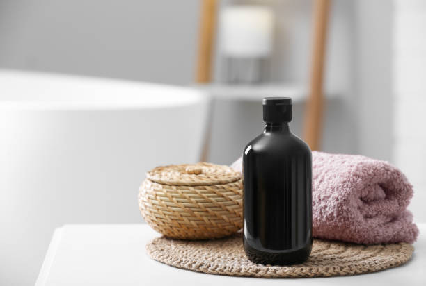 istock Bottle of bubble bath, towel and wicker box on white table in bathroom, space for text 1453140452