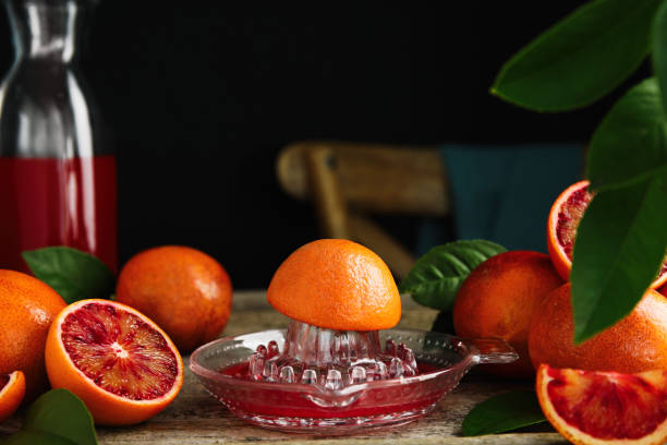 istock Squeezer with half of sicilian orange on wooden table, space for text 1453140917
