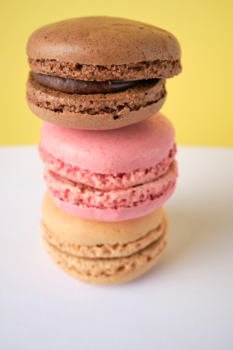 Stack of three macaroons against a yellow background.