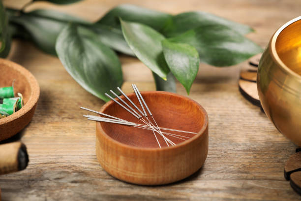 cuenco con agujas de acupuntura sobre mesa de madera - acupuncture needle fotografías e imágenes de stock