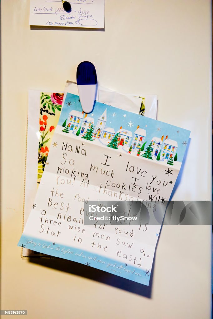 Modern refrigerator door with child's notes and magnets in kitchen Modern refrigerator door with child's notes and magnets in kitchen, close up. Adhesive Note Stock Photo