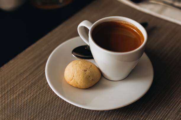 istock White cup of hot espresso coffee with a cookie on the table 1453145807