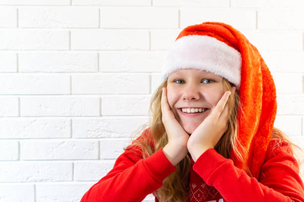 Close-up photo of a smiling miss in a Santa hat looking into a camera with a place to copy Close-up photo of a smiling miss in a Santa hat looking into a camera with a place to copy 12 17 months stock pictures, royalty-free photos & images