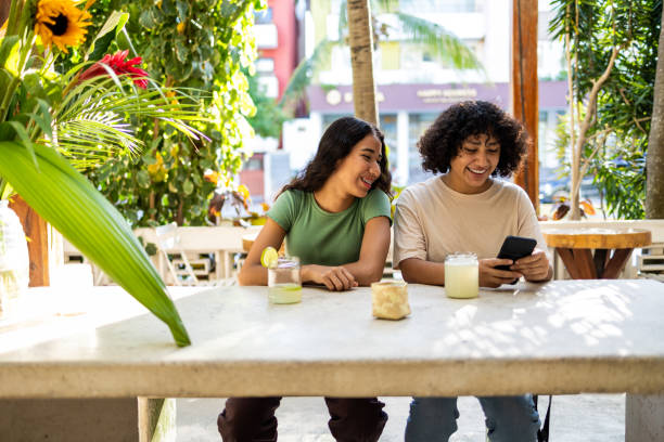 istock Friend sitting at the cafe and using mobile phone 1453155848