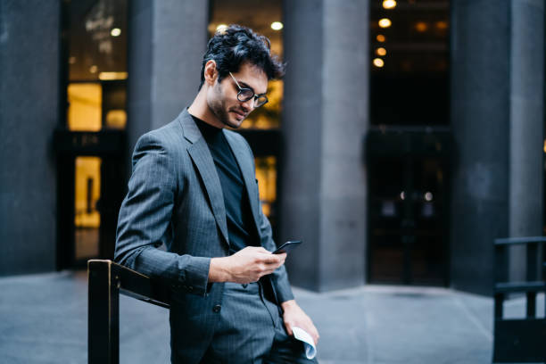 istock Confident male entrepreneur in stylish glasses checking received cellphone notification during web chatting via smartphone app, businessman in trendy eyewear searching sms message on mobile gadget 1453159080