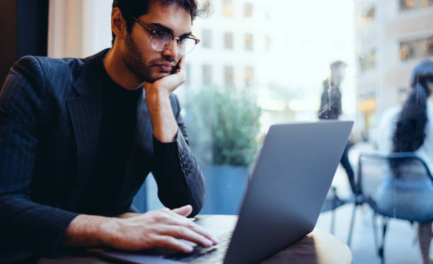 istock Pensive male economist dressed in formal clothes watching tutorial via high speed internet connection on digital netbook sitting in cafe interior, pondering businessman reading news on netbook 1453159110