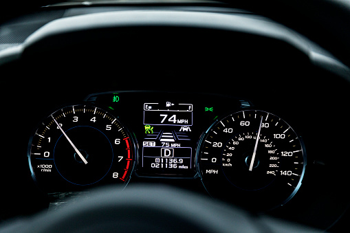 Car dashboard speedometer, tachometer, fuel gauge, etc display close-up while car is traveling at 74 miles per hour.