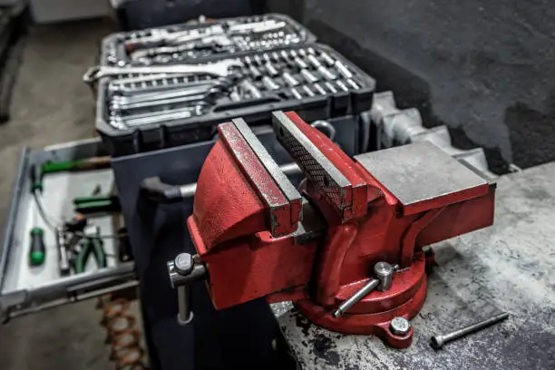 Professional red metal vice tool in a garage workshop