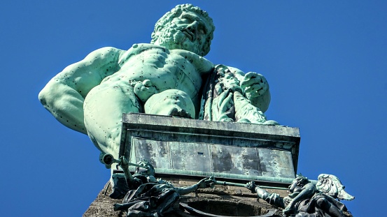 A low angle shot of the Hercules Statue monument against a blue sky in Kassel, Germany