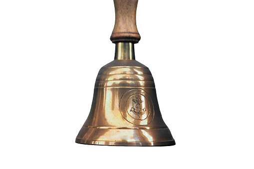 Old ship hand bell made of yellow metal with an anchor pattern, isolated on a white background
