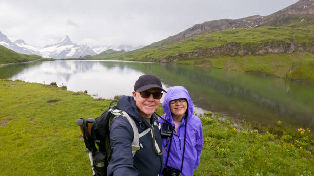 älteres paar, das im regen durch die schweizer alpen wandert, machen sie ein selfie-porträt in der nähe des bachalpsees auf dem gipfel von first, schweiz - schreckhorn stock-fotos und bilder