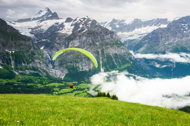 Tandem paragliding taking off the mountainside in the Swiss Alps near Grindelwald, Switzerland