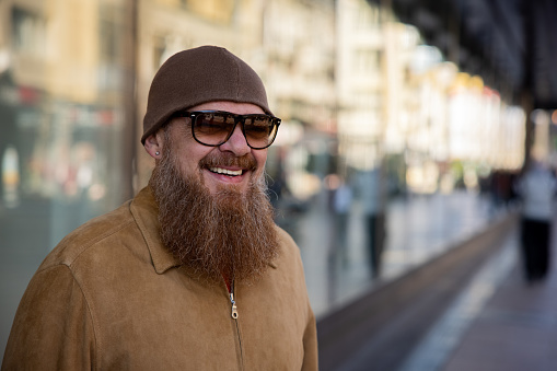 Headshot of urban mid-adult Caucasian man with long beard, in the city