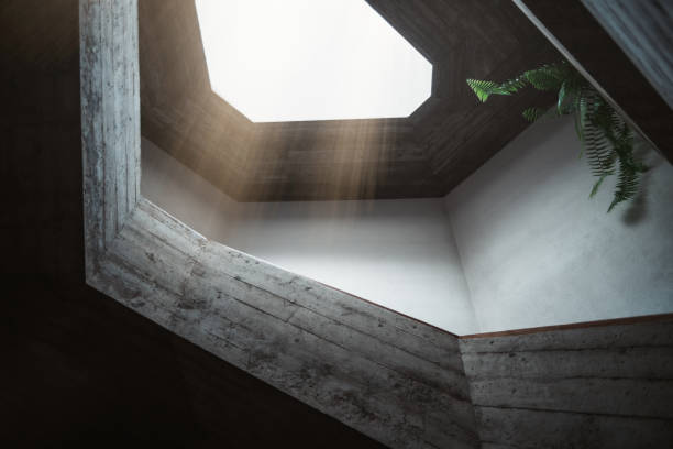 Skylight radiated from a window with an irregular shape in the roof of a church with a contemporary and modern architectural style, built with cement and plant leaves showing at the upper right corner