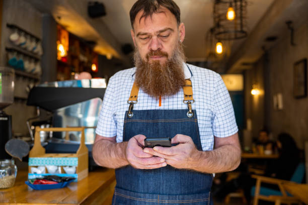istock Caucasian waiter using mobile phone at the coffee shop 1453180657