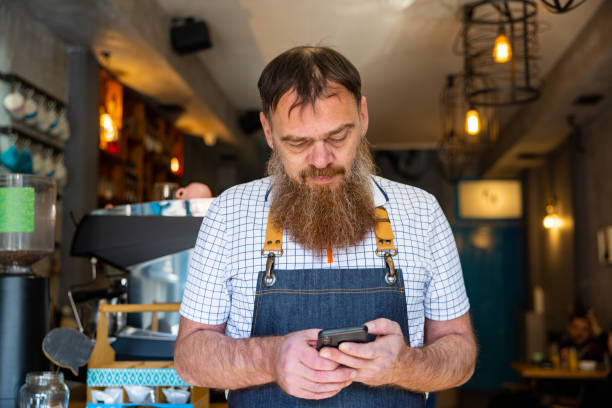 istock Caucasian waiter using mobile phone at the coffee shop 1453180661