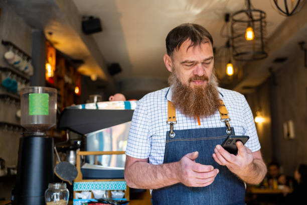 istock Caucasian waiter using mobile phone at the coffee shop 1453181234