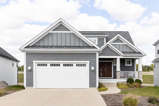 Elmhurst, IL, USA - September 25, 2022: A new, grey home with horizontal and vertical siding, white garage door, and covered front porch.