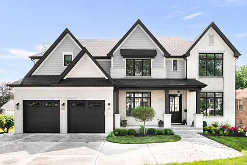 Chicago, IL, USA - June 14, 2020: A beautiful modern farmhouse with grey siding and white brick, black framed windows, and landscaping.
