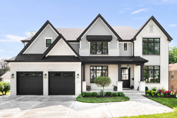 A grey and white modern farmhouse with black accents. Chicago, IL, USA - June 14, 2020: A beautiful modern farmhouse with grey siding and white brick, black framed windows, and landscaping. farmhouse stock pictures, royalty-free photos & images