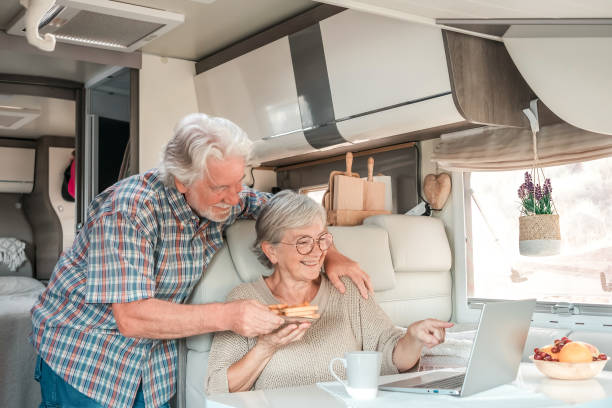 istock Senior beautiful couple in travel vacation inside a camper van browsing on laptop while enjoy breakfast together 1453189682