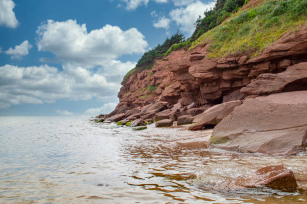 Cloudy basin head rocks Basin Head beach, Prince Edward Island with red rock cliffs cavendish beach at prince edward island national park canada stock pictures, royalty-free photos & images