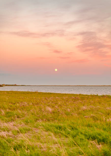 Isle De Madeleine moonrise at sunset  2 Isle De Madeleine moonrise at sunset with a colourful sky. cavendish beach at prince edward island national park canada stock pictures, royalty-free photos & images