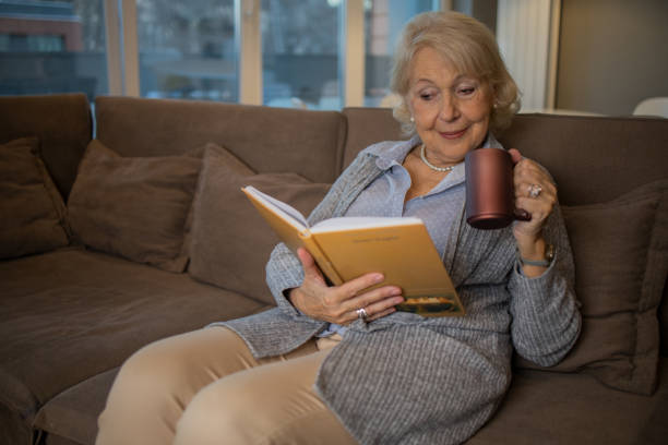 istock Happy woman reading book at home 1453219165