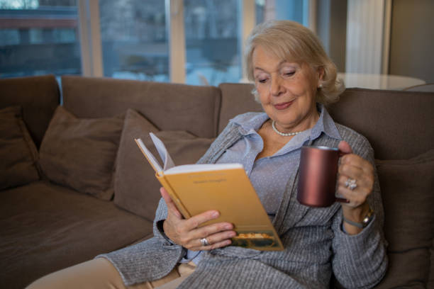 istock Happy woman reading book at home 1453219199
