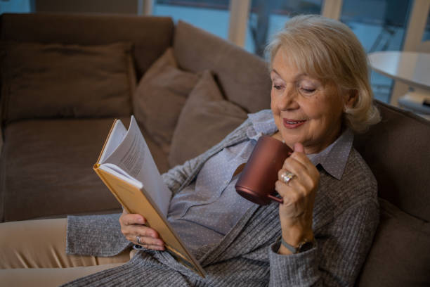 istock Happy woman reading book at home 1453219201