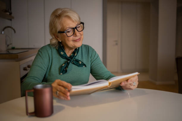 istock Happy woman reading book at home 1453219209