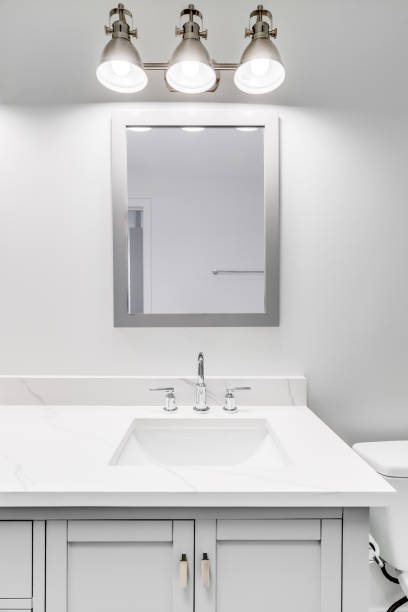 istock A bathroom's grey cabinet and bronze light shining over the marble countertop. 1453223693