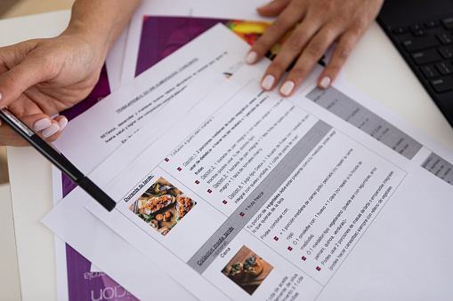 Latin american nutritionist and deportologist woman hands pointing out a diet plan explaining her patient how to achieve a healthy and balanced diet with graphics, digit tablet and charts. Buenos Aires. Argentina