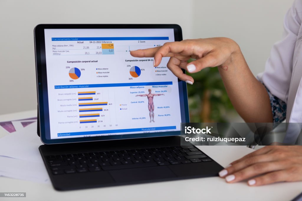 Close up of hands of a female nutricionist doctor and deportologist  pointing out  a document in her computer during a medical consultation Latin american nutritionist and deportologist's finger pointing at a body mass index study of a patient during a medical appointment Nutritionist Stock Photo