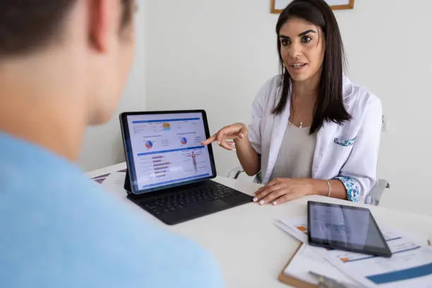 Photo of Female nutricionist doctor and deportologist in her desk's office during a medical consultation with teenager boy patient