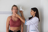 Female nutritionist and deportologist mesuring height on a female patient with anthropometric instruments during medical consultation