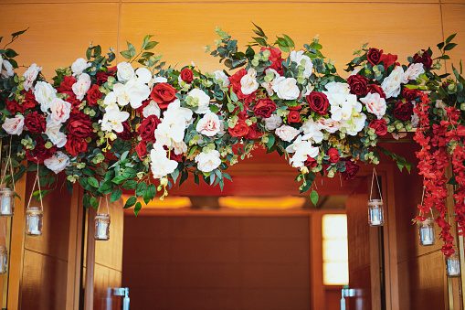 Original wedding floral decoration in with mini-vases and bouquets of flowers hanging from the ceiling and door arch.
