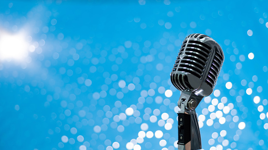 Retro microphone on shiny blue background.