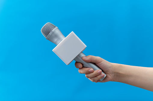 Rear view of female journalists holding microphone at a media event