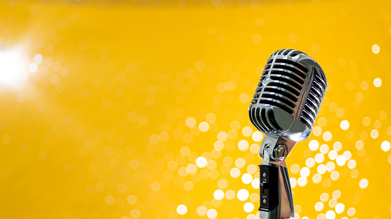 Retro microphone on shiny yellow background.